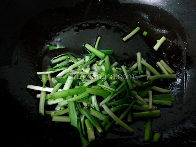 锅中油热后，先把韭菜茎炒一下，盛出备用。