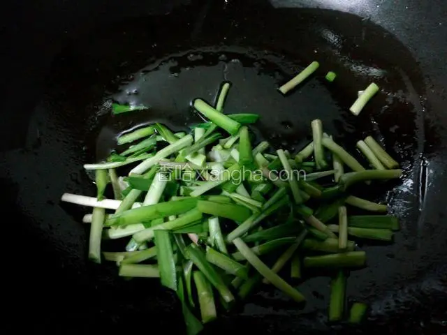 锅中油热后，先把韭菜茎炒一下，盛出备用。