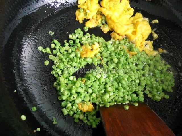 把炒熟的鸡蛋拨到一边，下入切好的豆角翻炒断生