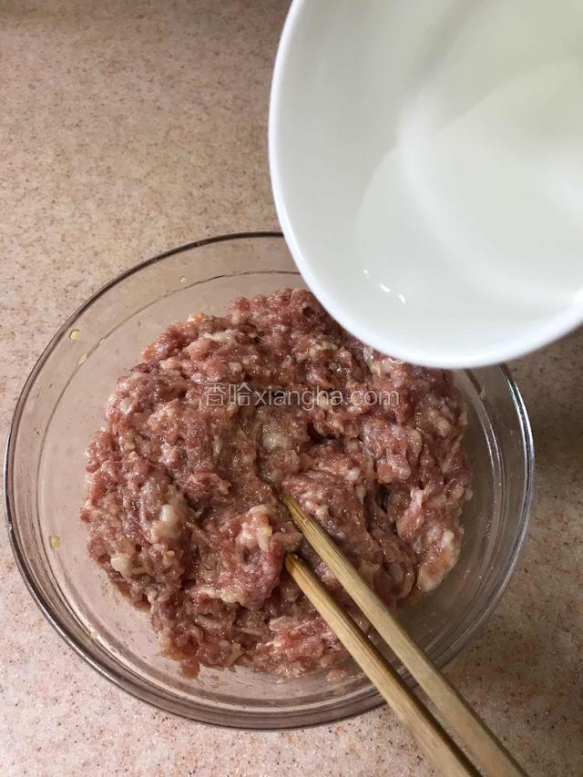 用筷子顺着一个方向搅拌至搅不动时加入少许清水继续搅（清水一次少加一些观察肉馅的吸水情况，可重复）