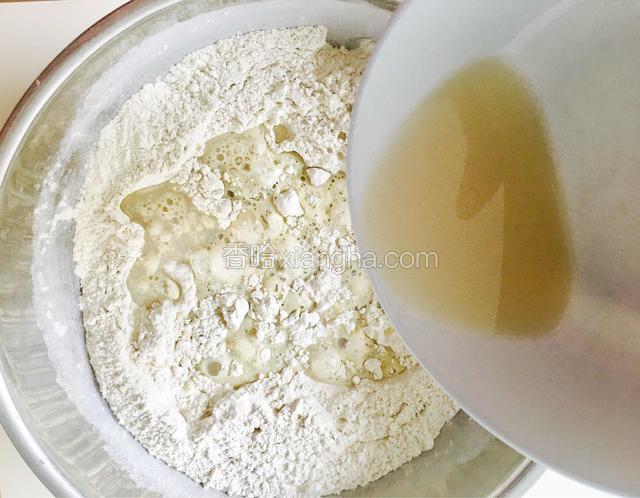 将酵母水缓缓地倒入面粉中。
