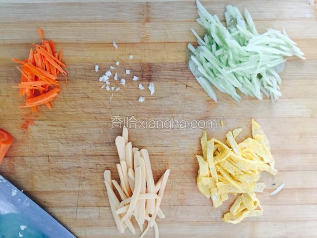 鱼肉肠、黄瓜、胡萝卜切丝。一个鸡蛋搅拌均匀后在平锅里煎个蛋饼切丝。蒜拍成蒜蓉。