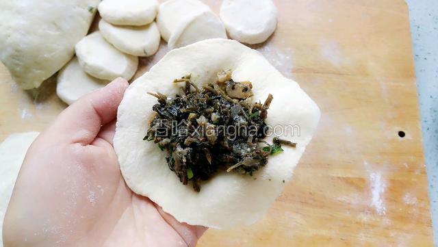 拿一个面皮放在左手掌，右手用筷子夹一些馅放在面皮中间。