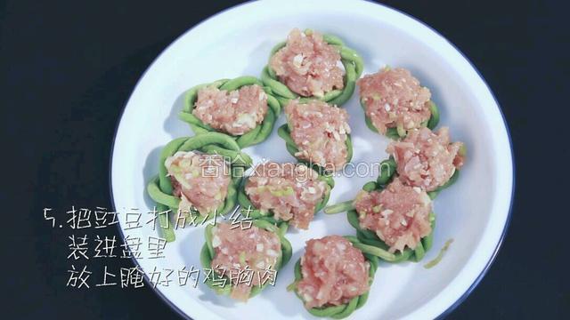 把之前焯过水的豇豆打成小结，装进盘中，放上腌制好的鸡胸肉。