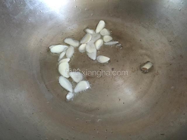 锅内放油烧至五成热，放入蒜片爆香。