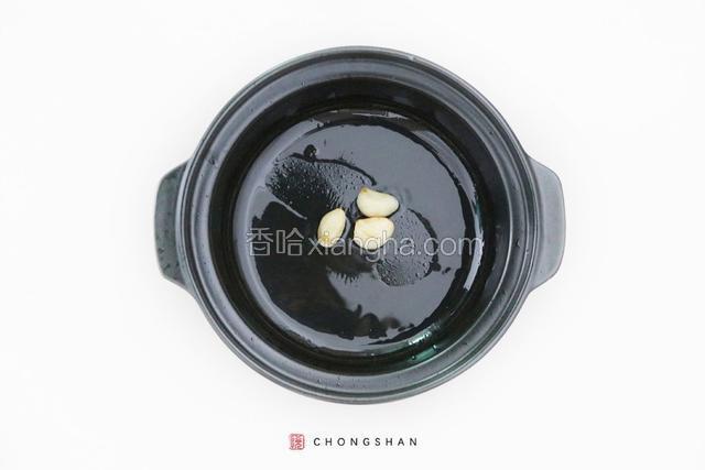 砂锅中倒入花生油，烧至六成热，放入大蒜粒煸炒至金黄。
