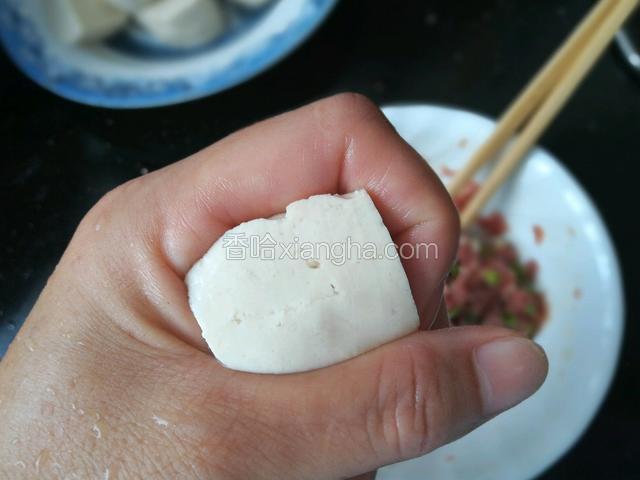 取一块豆腐放在虎口处稍微捏紧。