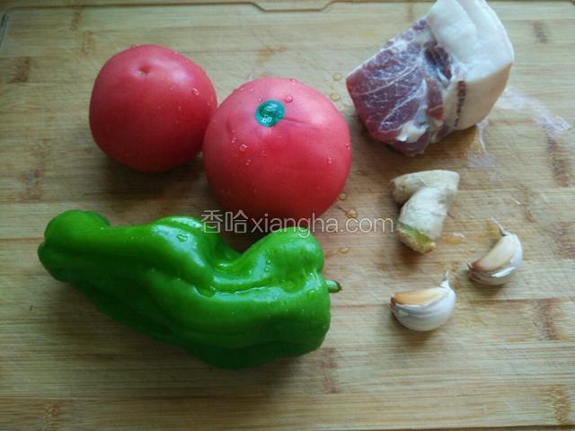 准备肥瘦相间的猪肉一块，西红柿青椒，这个青椒个头比较大，只用了一个，据说应该用辣一点的青椒，我家不太能吃辣，就用微辣一点的。还有生姜和蒜头,生姜只用到图中的小半块。