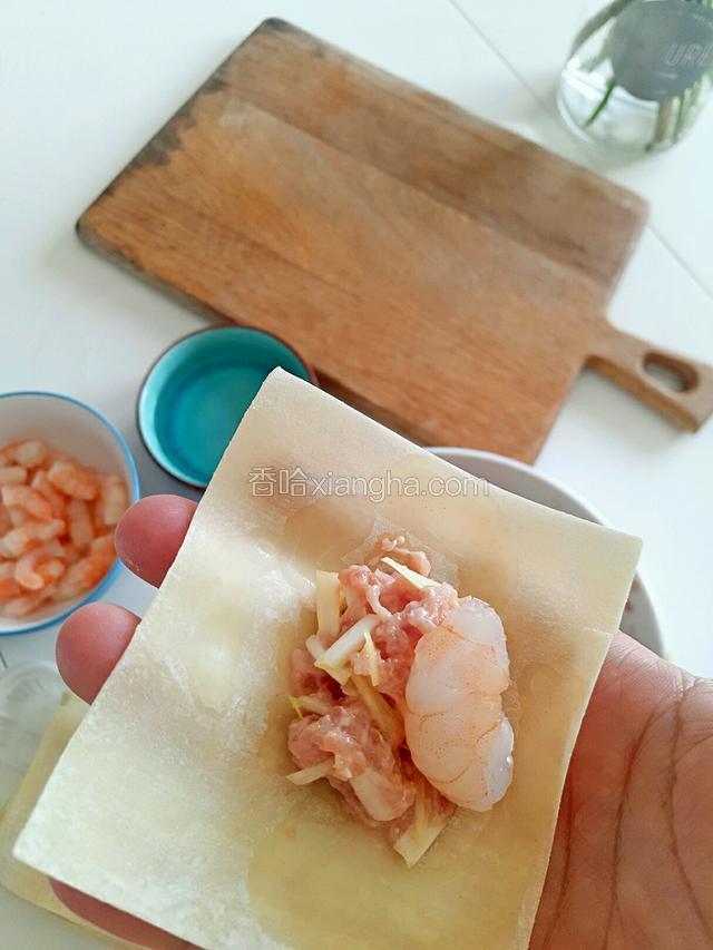 虾仁一开二…一开三嘟行，肉沫加虾仁…然后云吞皮周围蘸点水，用虎口捏紧…
