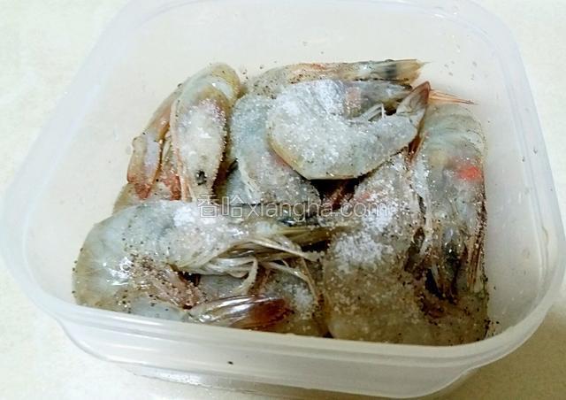 把洗好的大虾放入一个保鲜盒中，放入盐一大勺，料酒两勺，黑胡椒粉适量，拌匀放入冰箱冷藏腌制四个小时以上。（我是提前一晚腌好的。）
