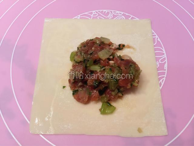 先取一张馄饨皮，用筷子夹取适量的肉馅放在馄饨皮中间稍靠下的位置。