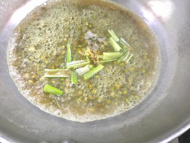 绿豆煮开后，放入姜末、葱段，中火煮十分钟