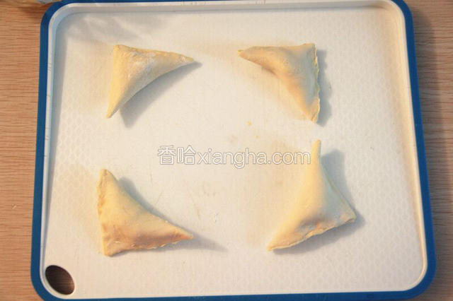 把榴莲果泥放在飞饼皮中央，饼皮斜角对折，包紧，取一把叉子轻轻压花边；