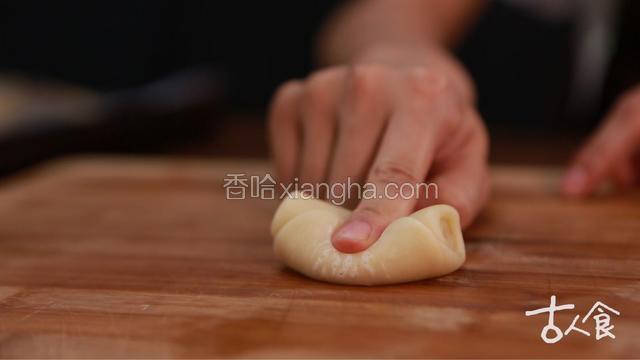 取一块用手指按压中间，将两头向中间捏，擀成圆形，放入馅料包起