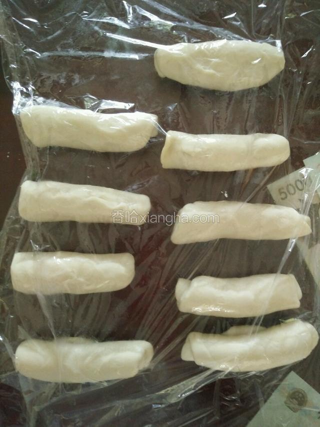 将油皮包在水油皮中。包好后口朝下，用擀面杖擀成长舌状，卷起。醒10分钟，要用保鲜膜盖好。