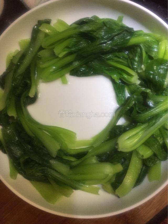 捞出油水断生的小青菜铺在碗底，