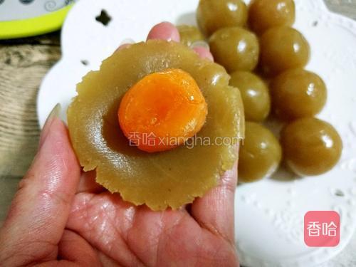 取一个莲蓉按扁成饼状，把蛋黄放在中间
