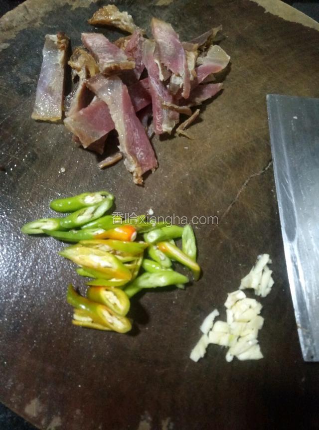 腊肉切片，美人椒切菱形，大蒜用刀拍烂。
