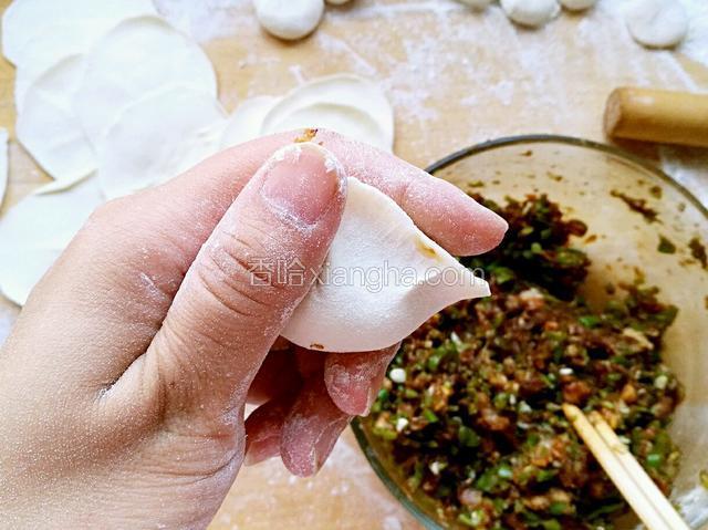 双手中指托起中间部位，两手拇指和食指同时捏紧两边饺子皮