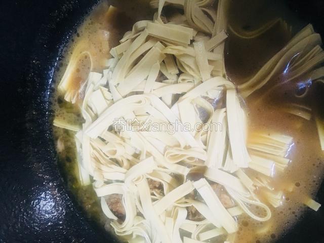 炖煮至骨头八成熟时加入豆腐皮继续炖煮