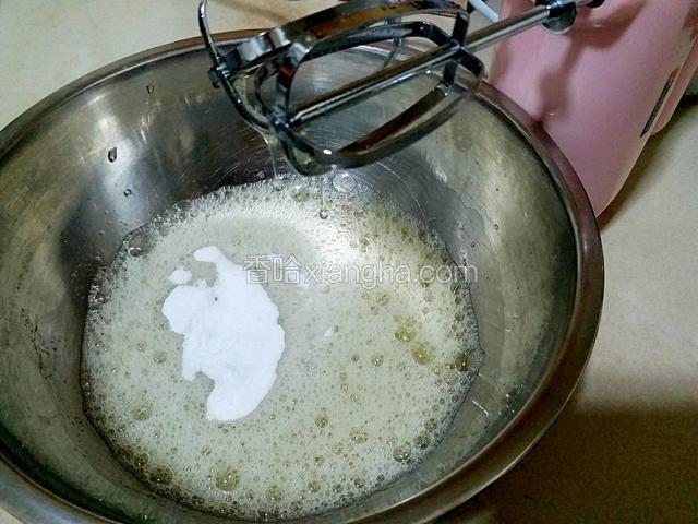 先给蛋白中第三滴白醋，用电动打蛋器低速打成鱼眼状，再加20克白糖。