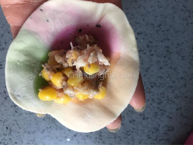 取饺子皮一个放手掌心，在皮子中间加入适量的饺子馅，