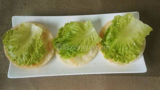 煎熟饺子皮放入盆里，铺上生菜叶