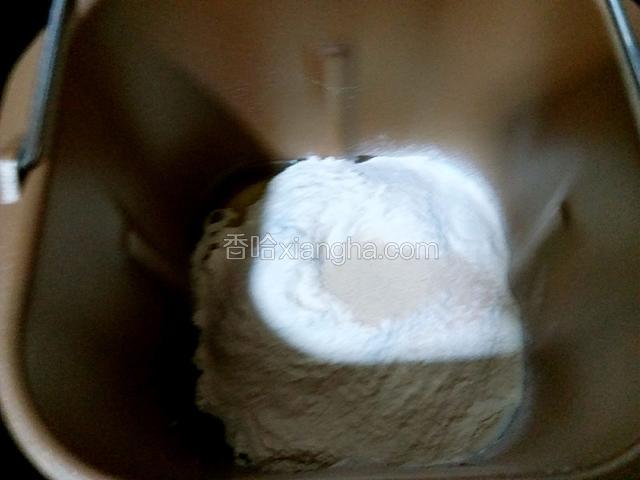 用手在面粉中间挖个小坑（如图）把酵母粉放入其中。
