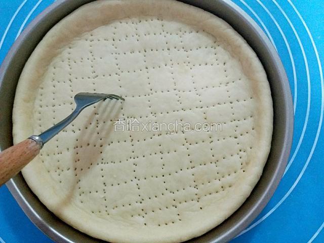 把擀好的面饼放入披萨盘中，如图用叉子扎小孔。
