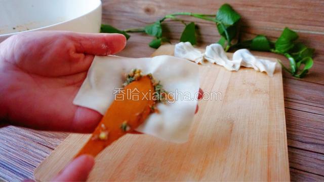 取一张馄饨皮，把馅料放在馄饨皮的中间