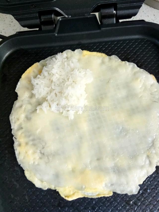 有蛋液的那面铁锅上，锅里再加一点油，面糊上面铺放糯米