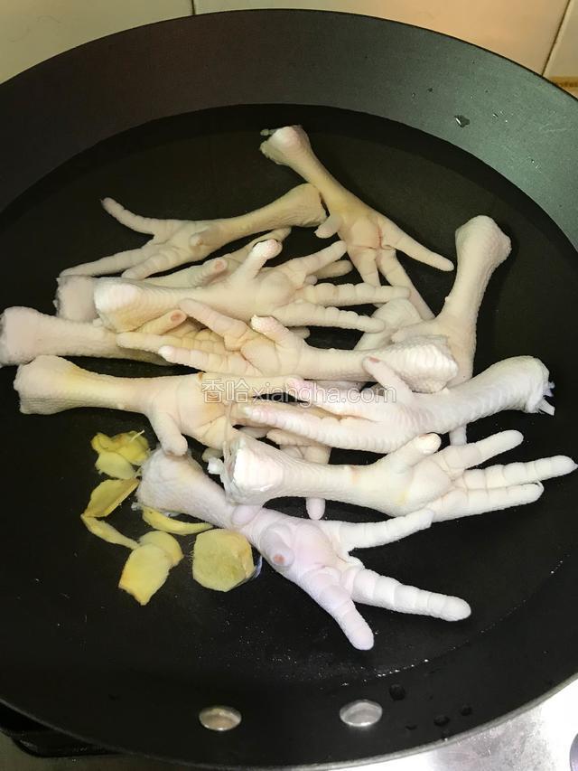 锅内加入适量清水、鸡爪冷水下锅并加入适量的料酒和姜片。