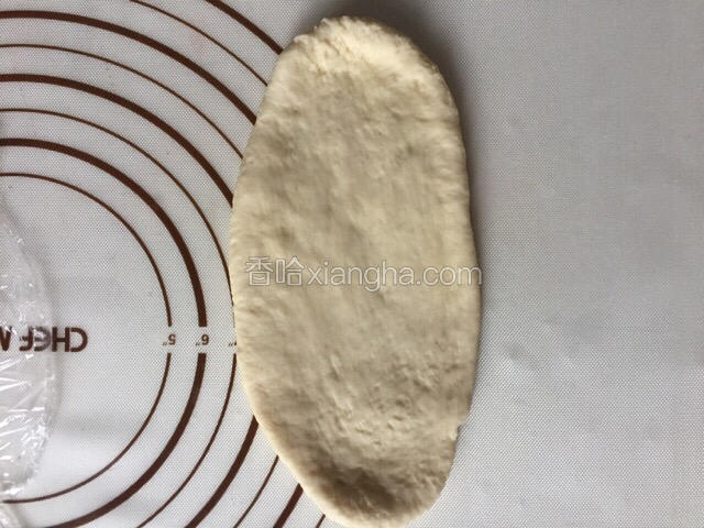 取出一个面团擀开成长舌状椭圆形