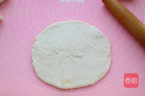 取一个面剂子将两边捏住，向中间捏到一起，然后擀成中间厚边缘薄的饼皮