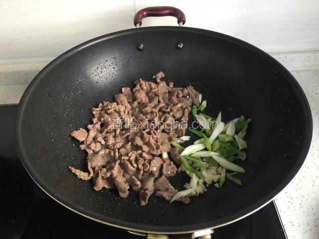 锅中放油烧热，倒入牛肉翻炒变色，放入葱花，蒜粒，姜粉炒香。