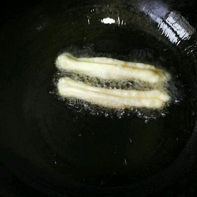 锅里的油烧热，扔进去个小面团能马上浮起来，面团周围有很多气泡就可以放油条了，油太凉的话油条蓬松不起来。捏住油条胚的两头轻轻拉长放入油锅。