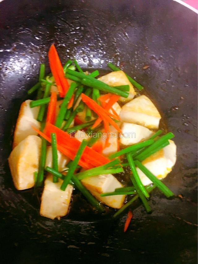 转中火，下入炸好的豆腐，再下葱段和胡萝卜丝