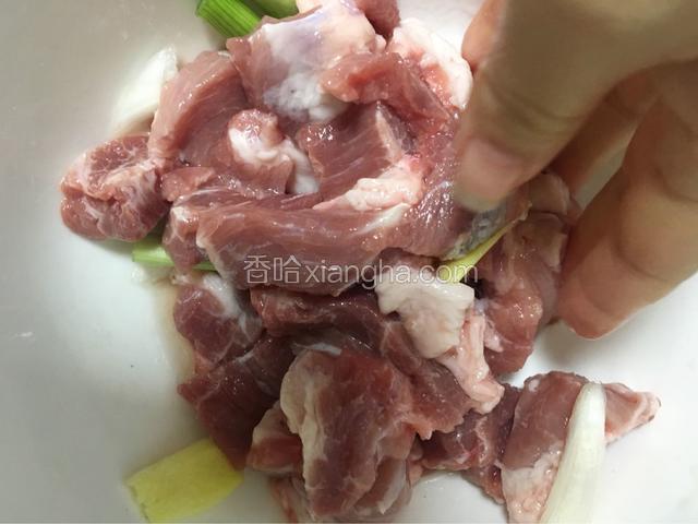 拿个盆装肉块，加入葱姜蒜，还有料酒和盐，抓匀腌制10分钟