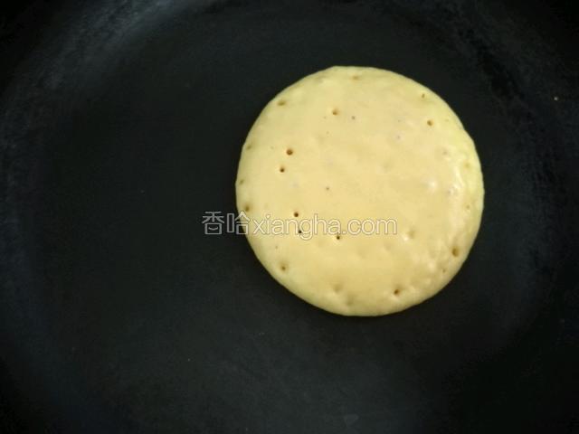 平底锅放开小火的煤气灶,挖一勺面糊提高倒入,自然会滴落成圆形,有小气泡炸开就翻面,依次摊好松饼。