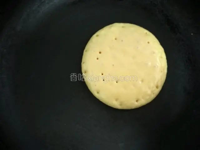 平底锅放开小火的煤气灶,挖一勺面糊提高倒入,自然会滴落成圆形,有小气泡炸开就翻面,依次摊好松饼。