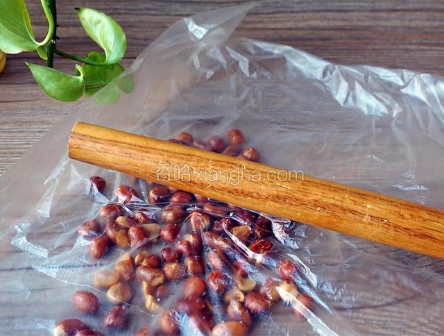 将晾凉的花生放入食品袋里，用棍棒敲碎