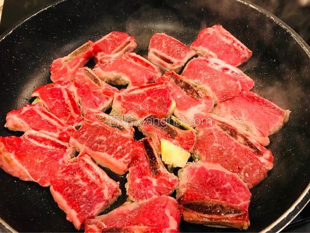 将不焦锅洒入少许食油烧热，放姜片爆香再将牛排骨进锅里香煎。