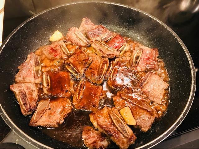 大火煮至调味料跟牛排骨变深色。一边煮一边翻炒大概5分钟将炉火转中火慢慢收汁5分钟左右。