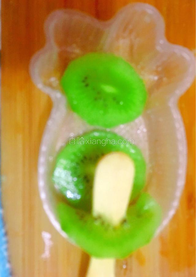 冰棒模具底部放入两片猕猴桃片，接口的地方也放一片猕猴桃片，棍子从中间插入（如图）