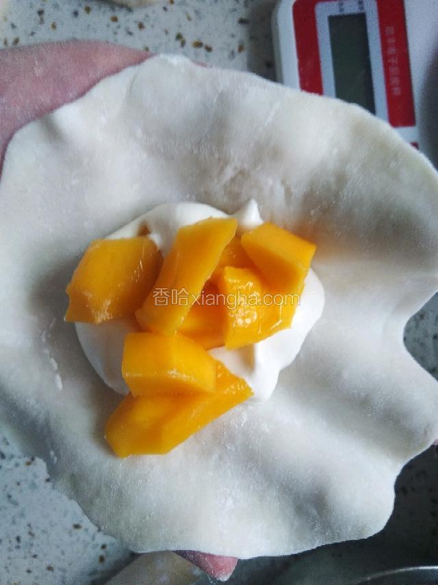 团子用擀面杖擀成薄皮，加入奶油和芒果丁