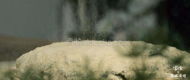 打好的糯米团放在洒满松花粉的案板上，再从上方筛下适量松花粉；