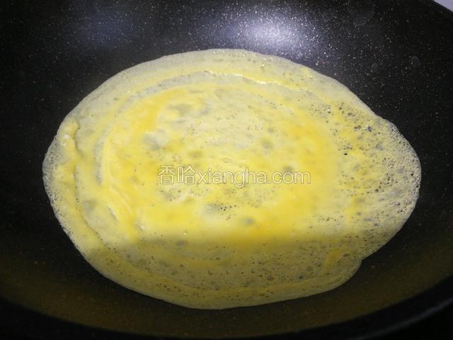 锅七成热时滴几滴植物油，倒入适量鸡蛋液，手握锅把轻轻转动，让鸡蛋液摊平。