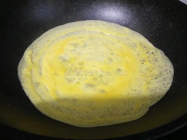 锅七成热时滴几滴植物油，倒入适量鸡蛋液，手握锅把轻轻转动，让鸡蛋液摊平。