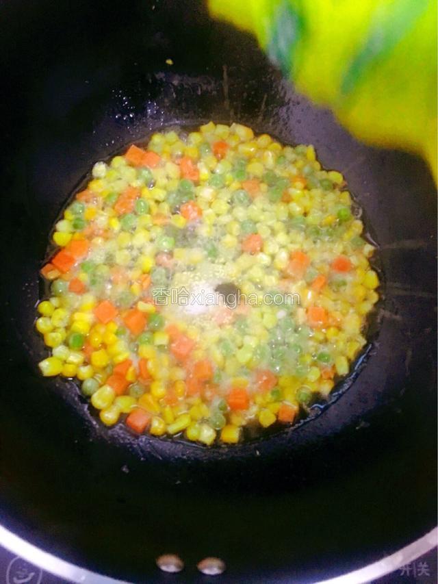 倒入杂蔬，加入少许盐，翻炒至青豆表面有点发白，以及盐巴融化