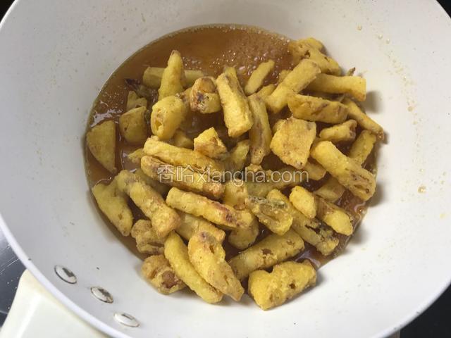 倒入炸好的菠萝条，翻拌均匀，使每根菠萝条都裹满糖浆